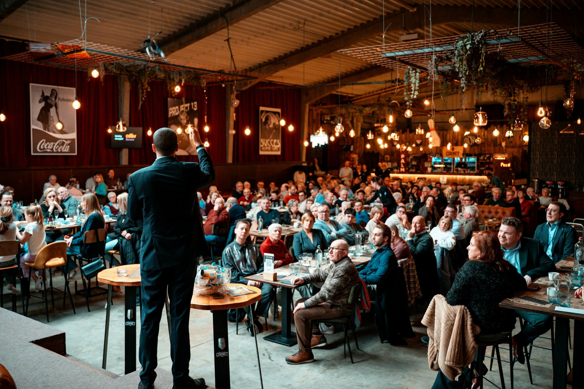 Man giving a speech before a full auction room.
