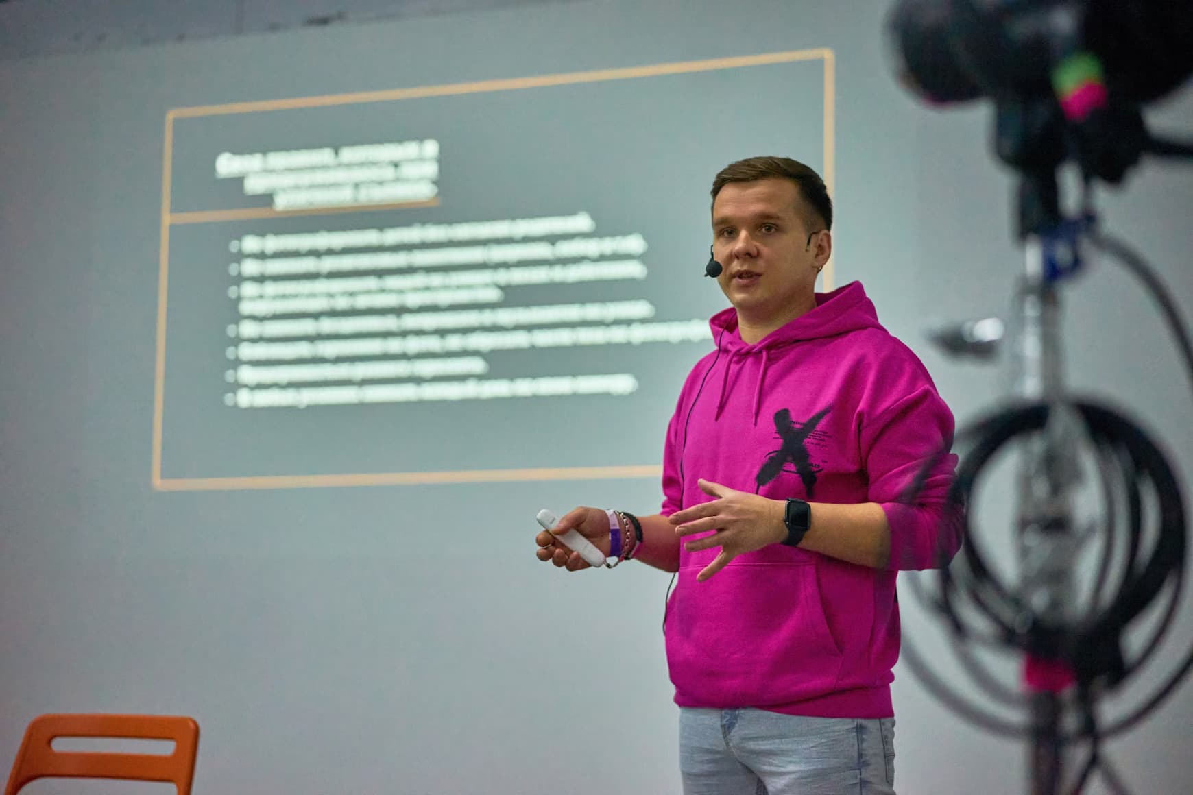 Intervenant en sweat rose donnant une présentation lors d’un colloque